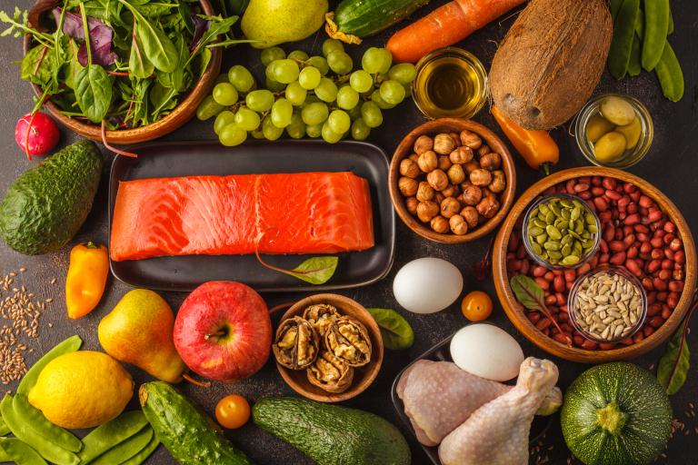 Elements of a Paleo diet, including fruits, salmon, poultry, nuts, eggs.